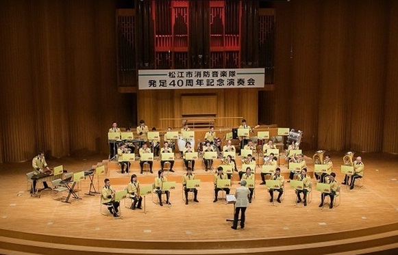 パイプオルガンのあるステージで演奏している消防音楽隊発足40周年記念演奏会の様子の写真