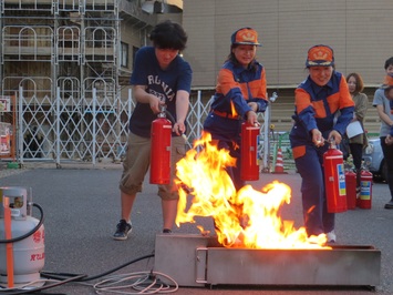 カメリア隊の方々と市民の方が消火器を使った訓練を行っている様子の写真