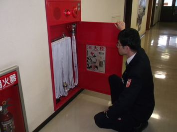 消防用設備(屋内消火栓)の入り口を開けて点検を行う消防職員の写真