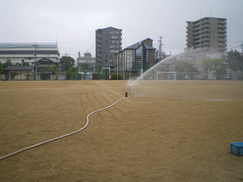 砂地にスプリンクラーで散水を行っている様子の写真