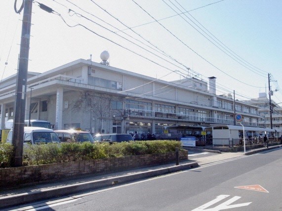 屋外に駐車場や駐輪場が設置されている3階建ての本館北棟の建物を道路の反対側から撮影した写真