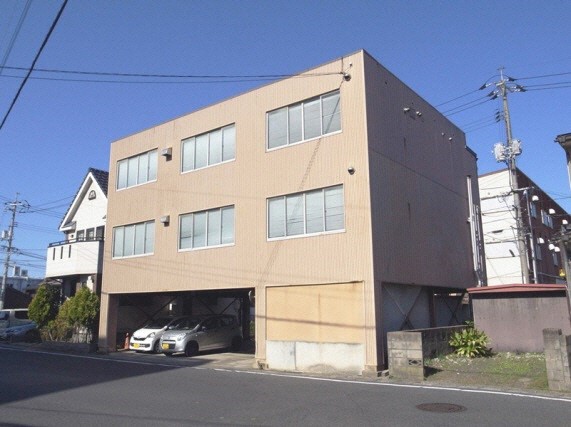 1階が乗用車3台の駐車スペースとなっている3階建ての職員会館の建物の写真