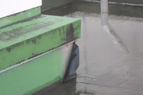 別館の屋上に水がたまり、左側の立上がり部の防水層が剥がれている写真