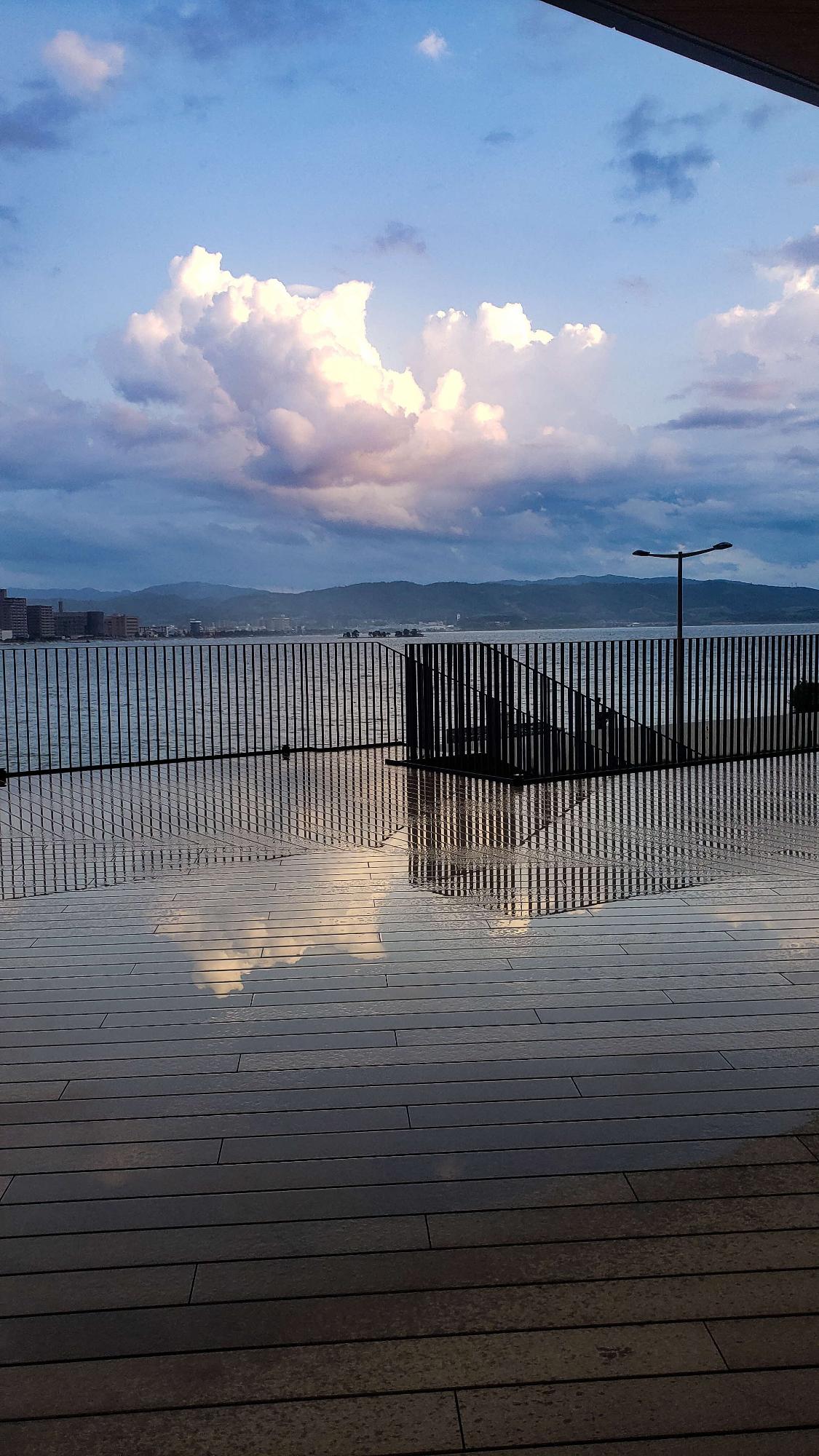 雨で濡れたテラスに青空が反射している写真