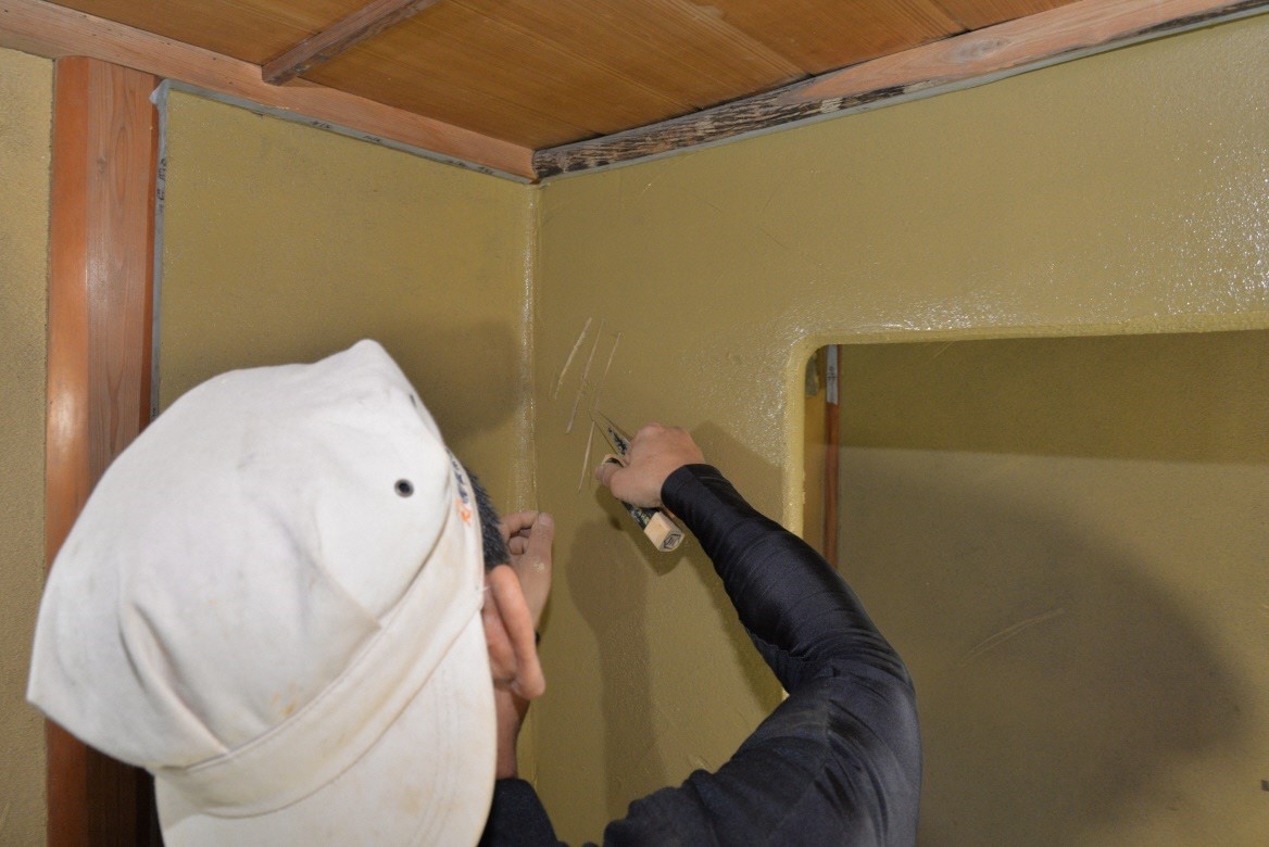 部屋の壁を上塗りしている左官職人の写真