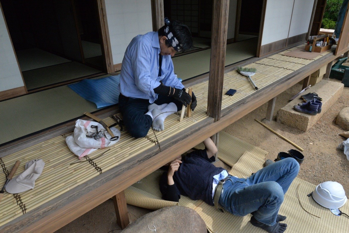 縁側の下に潜り込んでいる作業員と縁側で簀子を組んでいる作業員の写真