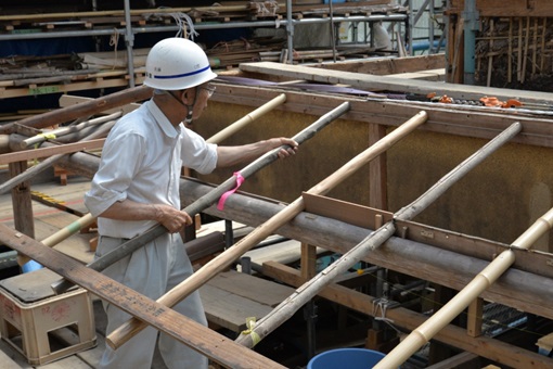 下屋庇に化粧垂木を取り付けている作業員の写真