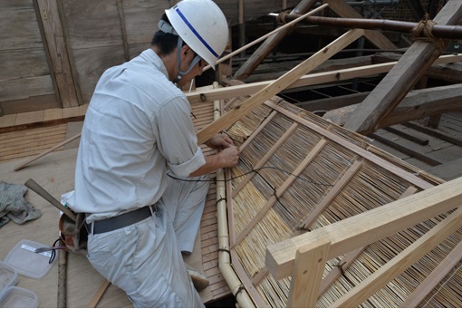 葭を編んで化粧屋根裏の修復をしている作業員の写真