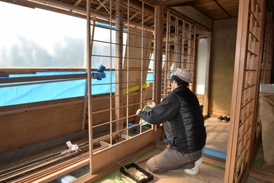 障子の格子状の骨組みを修復している作業員の写真