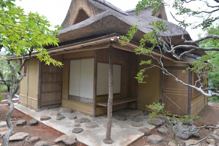 かやぶき屋根の下にひさしがあり、その下に土間たたきがある御風呂屋の建物の外観写真