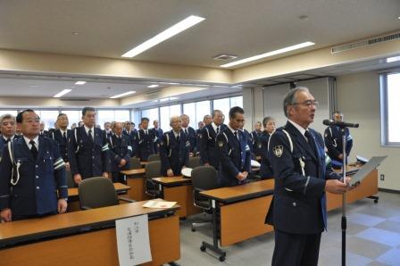 交通指導員の方たちが制服姿で仕事始め式に参加し、代表の方1名がマイクの前で話をしている写真