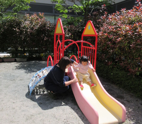 あいあいの中庭ですべり台をしている親子の写真