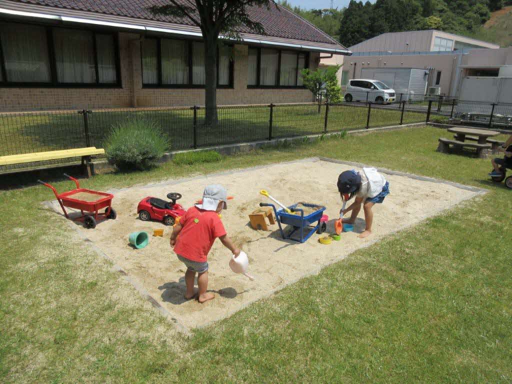 庭で砂遊びをする男児二人の写真