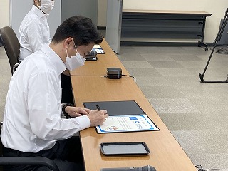 テーブルに置かれた締結書にサインをする男性の写真