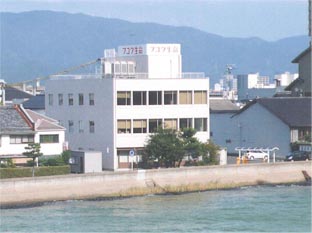 3階建ての白い建物の屋上に横に赤文字でフコク生命と書かれた大きな看板が設置された富国生命保険相互会社の外観写真