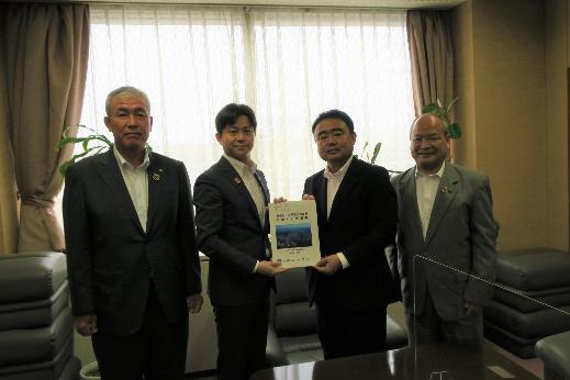 4名の男性が横一列に並び、中央に立つ森戸義貴中国地方整備局長と同盟会の男性が一緒に要望書を持っている集合写真