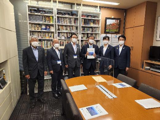 6名の男性が横一列に並び、中央に立つ石破茂衆議院議員と同盟会の男性が一緒に要望書を持っている集合写真