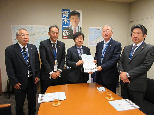 5名の男性が横一列に並び、中央に立つ青木一彦参議院議員と同盟会の男性が一緒に要望書を持っている集合写真