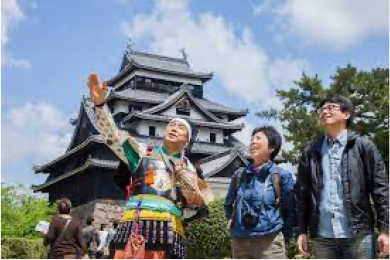 松江城を背景に鎧を付けた案内人が観光客を案内する様子