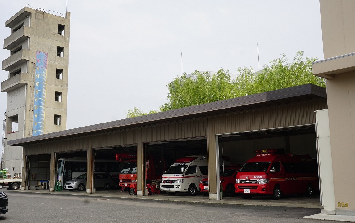 救急車、消防車、一般車、バスが別棟車庫に駐車されている様子を右斜め前方から写した写真