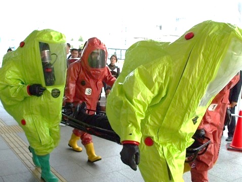 陽圧式科学防護服を着用してタンカを運ぶ訓練を行っている救助隊の方々の写真