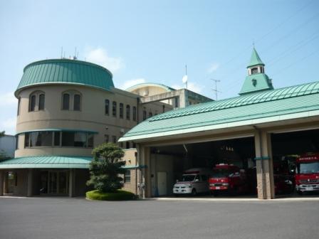 ベージュ色の壁に薄緑色の屋根で右側が車庫、庁舎が円形になっている松江市南消防署庁舎を正面右斜めから写した写真