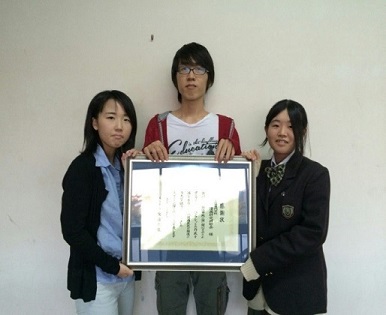 マンガ「ハコモノ計画」制作メンバーの雲藤さん、坂本さん、岸さんの3人で感謝状を持っている写真