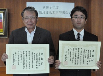 代表取締役の藤岡氏と主任技術者の周藤氏が表彰状を手にして並んでいる写真