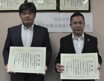 代表取締役の美田氏と主任技術者の高本氏が表彰状を手にして並んでいる写真