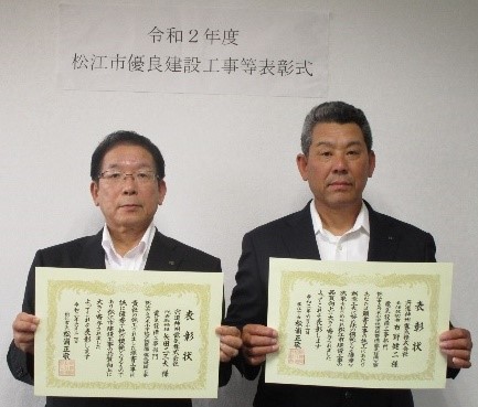 代表取締役の矢田氏と主任技術者の布野氏が表彰状を手にして並んでいる写真