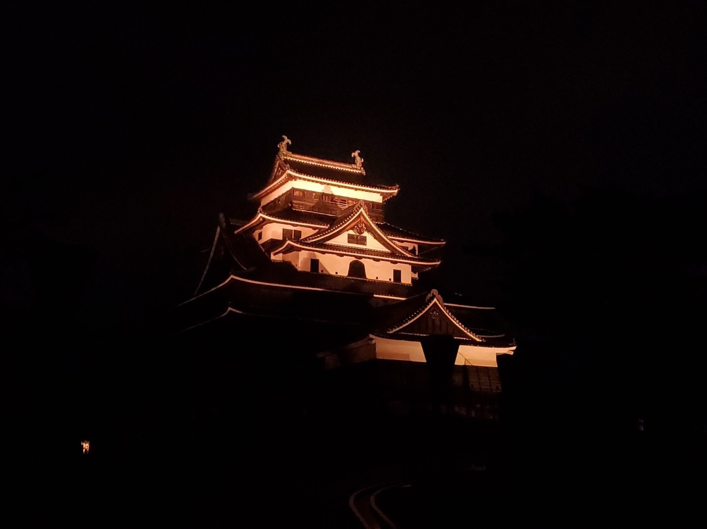 夜にオレンジ色にライトアップされた松江城の写真