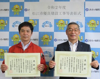 代表取締役の深田氏と主任技術者の今岡氏が表彰状を手にして並んでいる写真