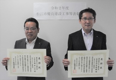 支社長の福井氏と管理技術者の伊達氏が表彰状を手にして並んでいる写真
