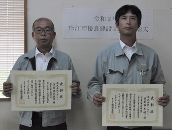 代表取締役の落部氏と主任技術者の横木氏が表彰状を手にして並んでいる写真