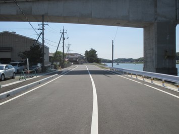 右側に海が見えるガードレールが設置された市道馬潟港1号線道路の写真