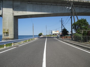 左側に海が見えるガードレールが設置された市道馬潟港1号線道路の写真