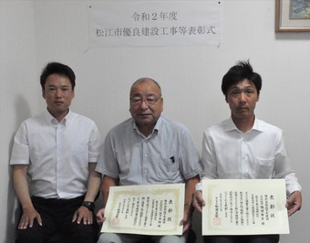 代表取締役社長の佐々木氏と主任技術者の稲田氏と工事担当者の石倉氏が表彰状を手にして並んでいる写真