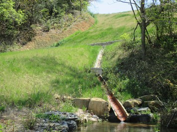 水の流れる人工水路が設置された農道の写真