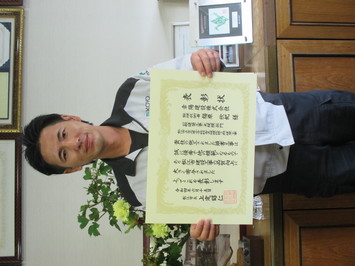 表彰状を持って正面に向けている幸陽建設株式会社の福原欣紀氏の写真