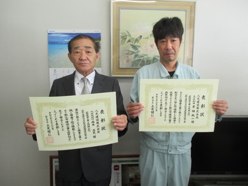 代表取締役の森本氏と主任技術者の吉畑氏が表彰状を手にして並んでいる写真
