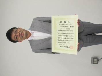 表彰状を持って正面に向けている株式会社共立エンジニヤの角橋健氏の写真
