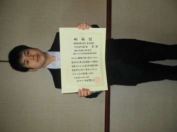 表彰状を持って正面に向けている島根電工株式会社松江営業所の影井明氏の写真