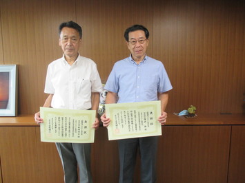 代表取締役の陶山氏と管理技術者の松崎氏が表彰状を手にして並んでいる写真