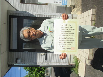 表彰状を持って正面に向けているマツチカ株式会社の加藤功志郎氏の写真
