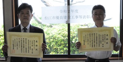 代表取締役の栂と管理技術者の稲田氏が表彰状を手にして並んでいる写真