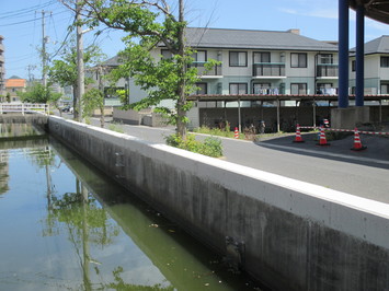 右側に住宅が見える水路護岸の嵩上げを行った黒田町雨水渠の写真