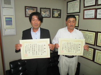 代表取締役の永田氏と主任技術者の笹木氏が表彰状を手にして並んでいる写真