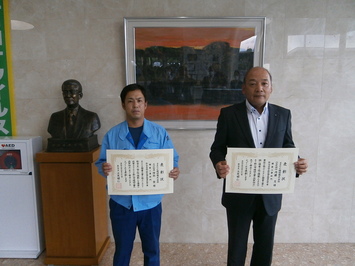 代表取締役の内藤氏と主任技術者の陸部氏が表彰状を手にして並んでいる写真