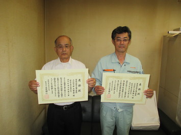 代表取締役の三島氏と主任技術者の井上氏が表彰状を手にして並んでいる写真