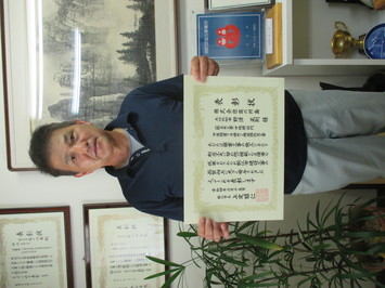 表彰状を持って正面に向けている株式会社庭の川島の野津正則氏の写真
